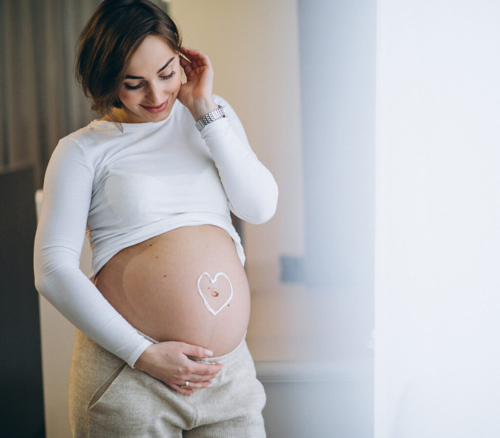 Pregnant woman applying cream on the belly to prevent stretches