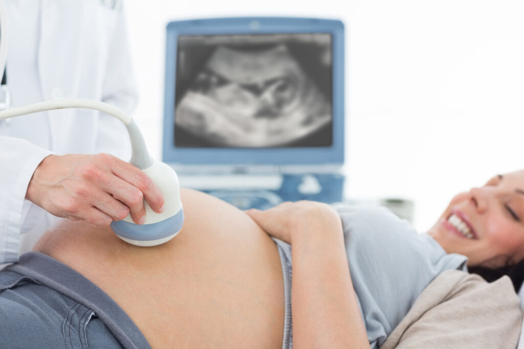 Cropped image of doctor performing ultrasound on pregnant woman in clinic